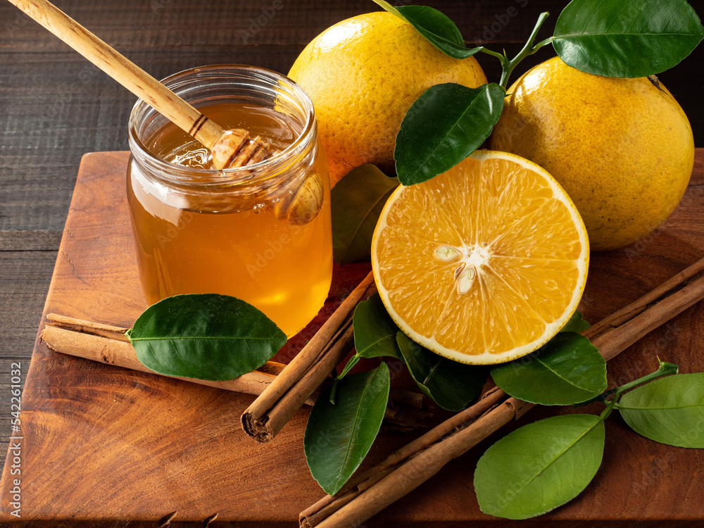 Miel de abeja con naranjas y canela en una tabla de madera.